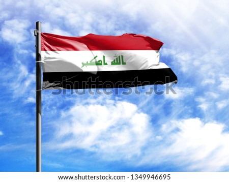 National flag of Iraq on a flagpole in front of blue sky.
