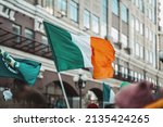 National Flag of Ireland close-up above people crowd, city street, traditional carnival of St. Patrick