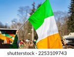 National Flag of Ireland close-up above people crowd people, traditional carnival of St. Patrick