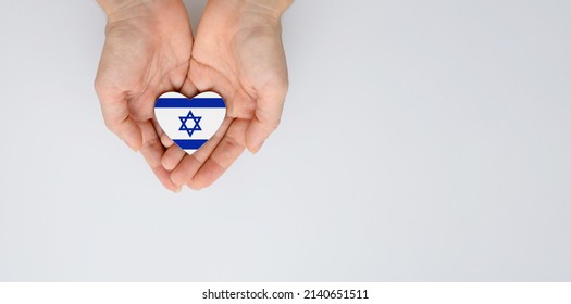 The national flag of Israel with the coat of arms in female hands. Flat lay, copy space.