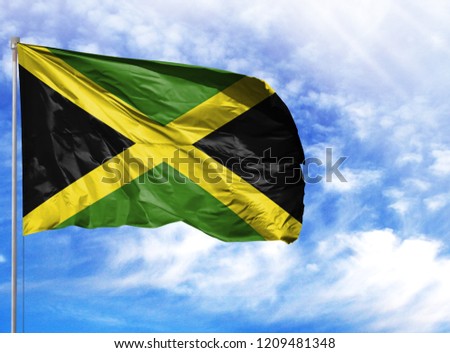 National flag of Jamaica on a flagpole in front of blue sky