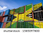 The national flag of Jamaica on a large number of metal containers for storing goods stacked in rows on top of each other. Conception of storage of goods by importers, exporters