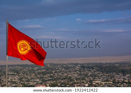 National flag of Kyrgyzstan on the background of the city of Osh