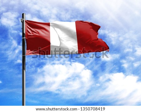 National flag of Peru on a flagpole in front of blue sky.