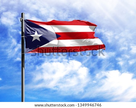 National flag of Puerto Rico on a flagpole in front of blue sky.