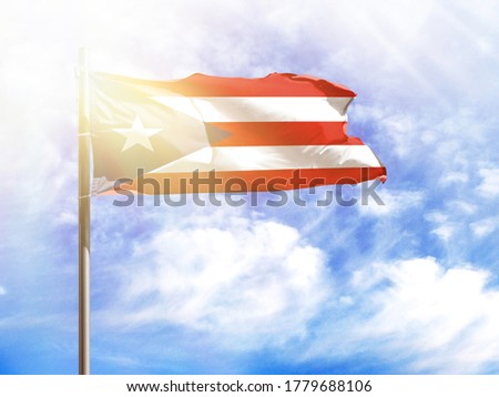 National flag of Puerto Rico on a flagpole in front of blue sky