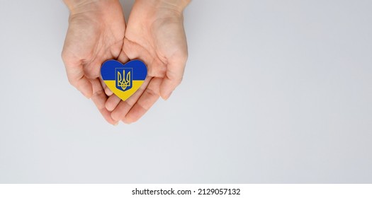 The national flag of ukraine with the coat of arms in female hands. Flat lay, copy space.