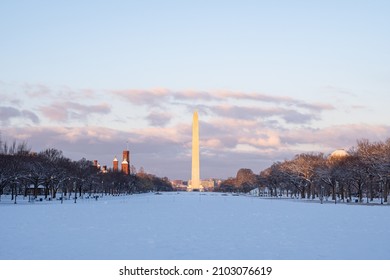 The National Mall and the Washington Monument covered in snow during sunrise right after a snowstorm.