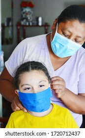 Native American Woman Helping To Put On The Mask To Her Little Daughter.