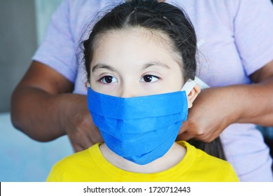 Native American Woman Helping To Put On The Mask To Her Little Daughter.