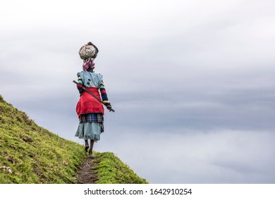 Native Black African Woman Carries A Load On Her Head In The Hills Of South Africa