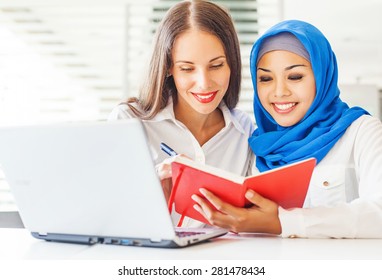 Native speaker teaching a muslim asian girl in a light classroom in college - Powered by Shutterstock