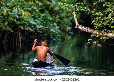 Einheimischer Stammesmann, der in Amazonas Regenwald in handgefertigtem Boot schwimmt