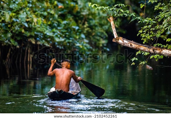 Native tribal man swimming in amazonia rainforest in\
handmade boat