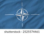 Nato flag depicted on folded wavy fabric of old cloth close up