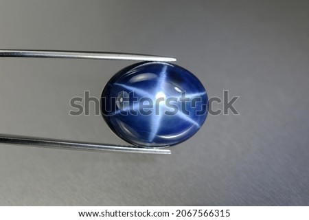 Natural 6 rays blue star sapphire gemstone in tweezers. Heated, diffusion treated, opaque, oval cabochon polished loose setting for making jewelry. Natural mined genuine corundum. Gemology, mineralogy Stock photo © 