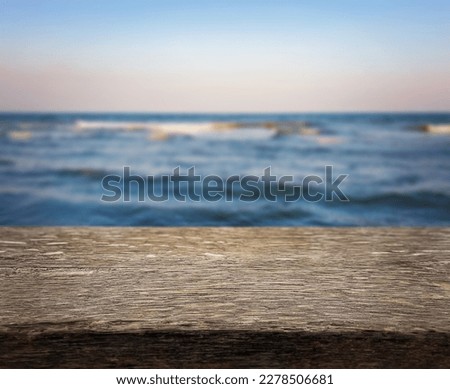 Natural, abstract, unfocused background. Seascape. An empty wooden base, a wooden table, a tabletop against the background of sunset, dawn on the seashore. Copy space