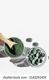 natural additives and superfood. green spirulina algae powder and pills in glass bowls on white background. healthy lifestyle concept. organic food