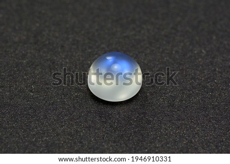 Natural adularia blue sheen round cabochon moonstone. Loose gem on gray textured leather background. Feldspar mineral group. Semiprecious gemstone not common relatively rare and expensive specimen Imagine de stoc © 