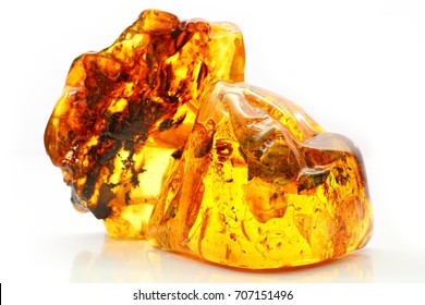 Natural amber. Two extraordinarily beautiful pieces of transparent yellow amber with inclusions on a white background with a bokeh effect. A natural mineral for jewelry. Color texture of sunstone