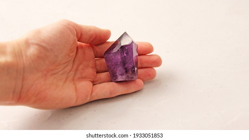 Natural amethyst stone is on a woman's hand, in the palm of her hand, on a light background. Natural stones, crystals for magic, lithotherapy, geology, minerals, stone collection.