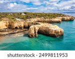 Natural arch above ocean, Arco de Albandeira, Algarve, Portugal. Stone arch at Praia de Albandeira, Lagoa, Algarve, Portugal. View of the natural arch Arco da Albandeira in the Algarve, Portugal.