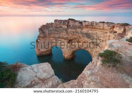 Natural arch above ocean. Natural caves at Marinha beach,  Algarve, Lagoa portugal. Stone arch at beach.
Summer season.