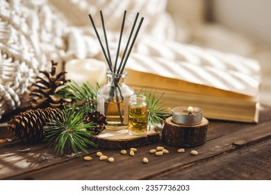 Natural aromatic scented reed diffuser air freshener bottle on wooden table with pine cone, burning candles. Christmas inspiration and mood, cozy home atmosphere, relax. Aromatherapy and decor - Powered by Shutterstock