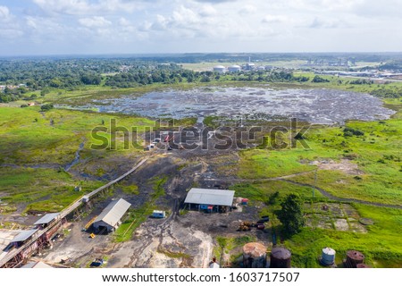 Natural asphalt mining factory and trains of red minecarts. Pitch Lake, the liquid asphalt lake, the largest natural deposit of bitumen in the world. La Brea, Trinidad island, Trinidad and Tobago.