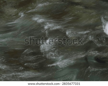 A natural background image capturing the surface of a clear stream flowing vigorously between rocks, with whitecaps visible.
