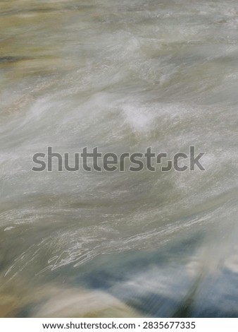 A natural background image capturing the surface of a clear stream flowing vigorously between rocks, with whitecaps visible.
