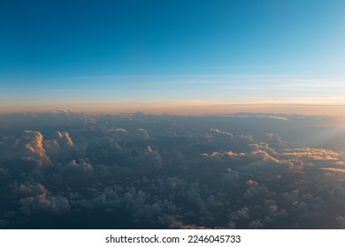 Natural background of sky, sunset above dark clouds, view from inside of airplane during the flight.