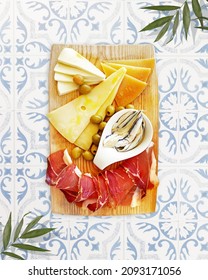 Natural balkan traditional food, Croatian plate. Ham, cheese sprinkled with olive oil with capers in a pickle with olives on a wooden dish on tile table.The perfect appetizer for wine