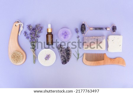 Natural bath accessories and self-care products for home body and skin care over purple background with lavender flowers. Natural herbal lavender cosmetics kit, eco living concept. Flat lay style