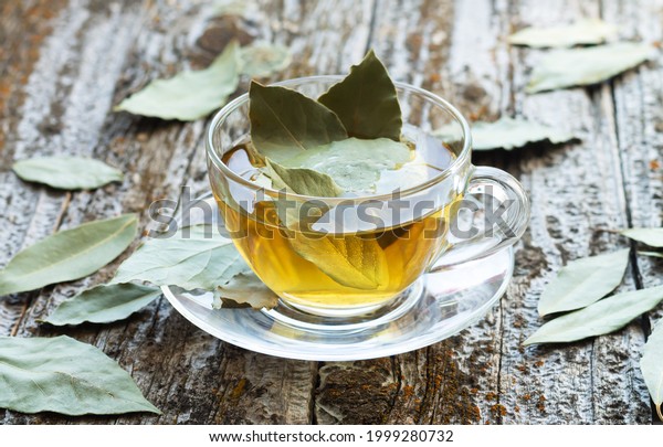 Natural bay leaf herbal tea in glass cup on rustic\
wooden table