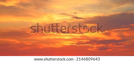 Natural beautiful bright saturated landscape view of sky sunrise or sunset with yellow orange red lilac clouds flying by small swallow birds on warm summer evening. Picture for wallpaper relaxation