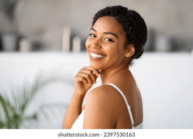 Natural Beauty. Attractive Black Woman Touching Chin And Looking At Camera While Standing In Bathroom At Home, Beautiful African American Female Enjoying Her Smooth Skin After Skincare Routine - Powered by Shutterstock