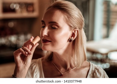 Natural beauty. Close up of delighted woman that keeping smile on her face while enjoying wine aroma
