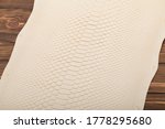 Natural beige-colored python leather folded on the wooden table 