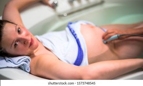 Natural birth in water. Woman giving birth in water. childbirth without pain. Midwife checks the heart beat of a child.