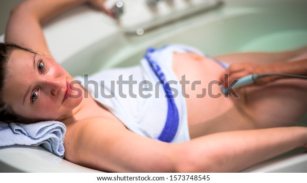 Natural
birth in water. Woman giving birth in water. childbirth without
pain. Midwife checks the heart beat of a
child.