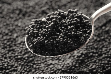 Natural black caviar and spoon as background, closeup