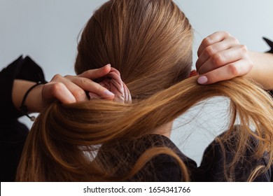 Natural blonde woman doing a ponytail, holding her hair, stop motion, back view, 