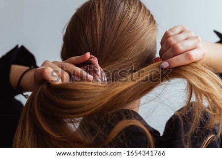 Natural blonde woman doing a ponytail, holding her hair, stop motion, back view, 