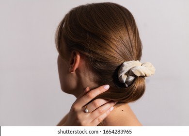 Natural Blonde Woman Holding Hair In Ponytail With Scrunchie. Side Perspective.