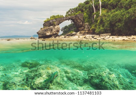 Natural bridge at Neil island, Andaman and Nicobar. Double photo under water and over water. View of the natural bridge, the main attraction of the island against the blue sky. snorkeling, diving