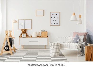 Natural, bright kid's bedroom interior with wooden furniture, designer accessories and posters on a white wall