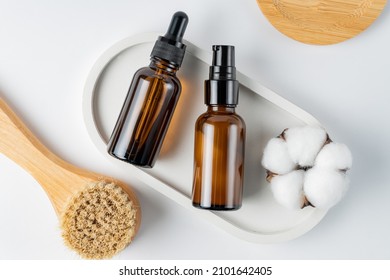 Natural bristles exfoliating brush for dry face or body massage on white background. two bottles with skin care products. Detoxing skin ritual. mockup