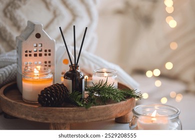 Natural Christmas essential oil, home aroma diffuser. Burning candles, branches of fir tree. Cinnamon, vanilla smell. Aromatherapy, cozy atmosphere, holiday festive mood. Close up macro, wooden table - Powered by Shutterstock