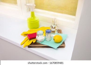 Natural Cleaners Concept. Natural Organic Eco Friendly Home Cleaning Ingredients, White Vinegar, Lemon, Baking Soda, Citric Acid On Wood Tray On Window Sill, Window On Background. Lot Of Copy Space.